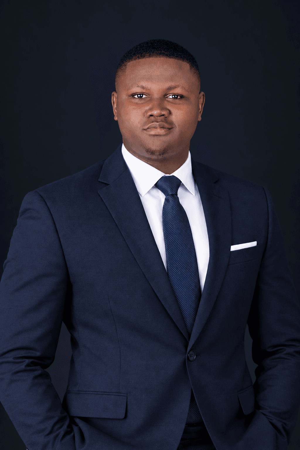 Studio portrait of Blessed Osezuwa Ariagbofo in a navy suit and tie.